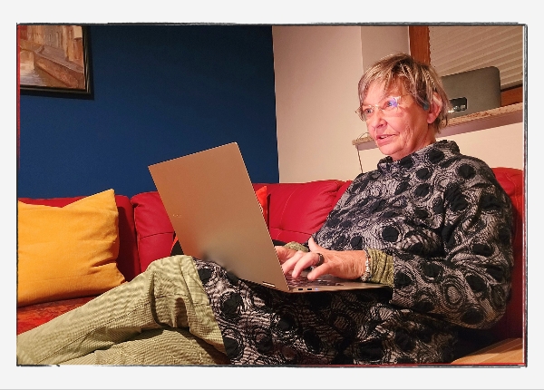 12 von 12 - Oktober 2024: Sylvia auf der Couch mit Laptop auf dem Schoß.